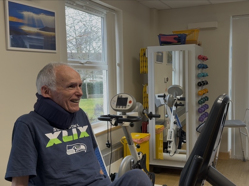kent-smiles-as-he-uses-an-exercise-bike-in-the-gym