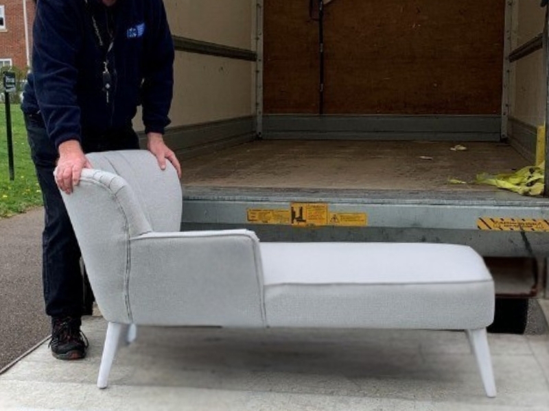 a-sofa-being-lifted-onto-the-back-of-an-empty-van