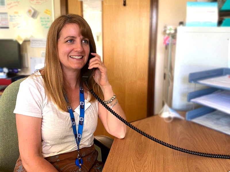 family-support-team-member-holds-phone-and-smiles