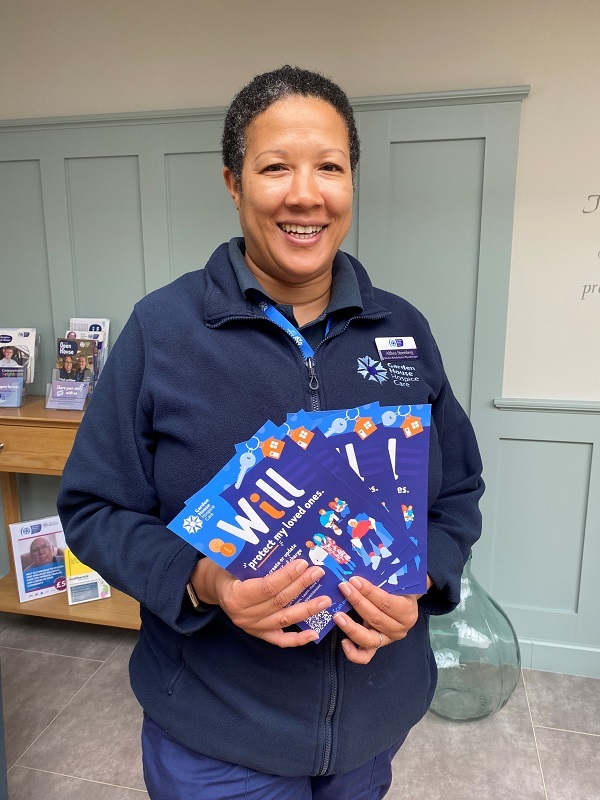 hospice-physiotherapist-althea-holds-make-a-will-leaflets-and-smiles