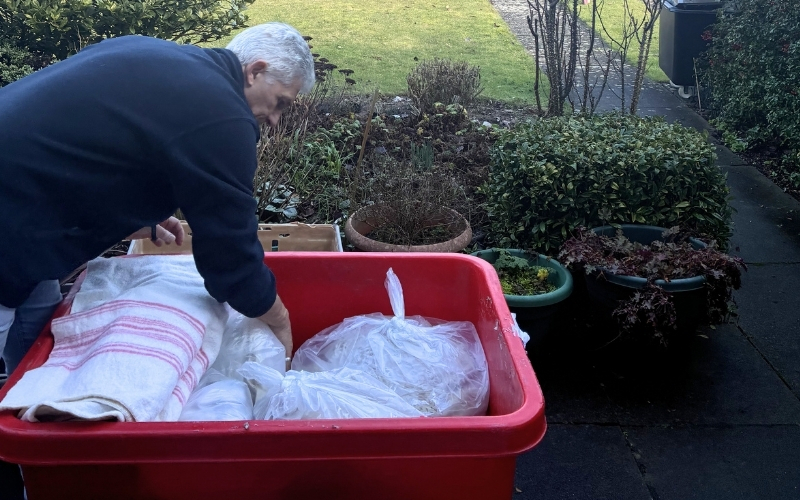 volunteer-sorting-donations-in-a-tapered-storage-box-on-a-house-clearance