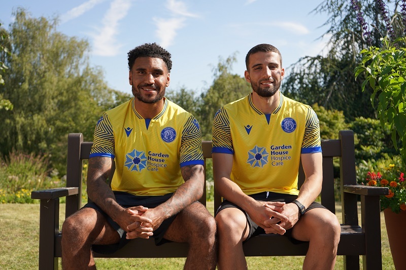 jamie-reid-and-nick-freeman-sat-on-bench-smiling-and-wearing-third-kit-shirts