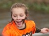 young-girl-smiles-as-she-crosses-stream-at-muddy-mayhem