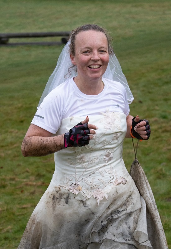 woman-smiling-while-running-in-muddy-wedding-dress