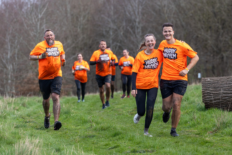 a-group-of-people-covered-in-mud-running-toward-the-camera