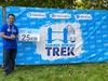 participant-holds-up-25km-sign-in-front-of-a-thames-bridges-trek-banner