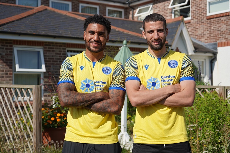 two-stevenage-players-stand-with-their-arms-folded-wearing-third-kit