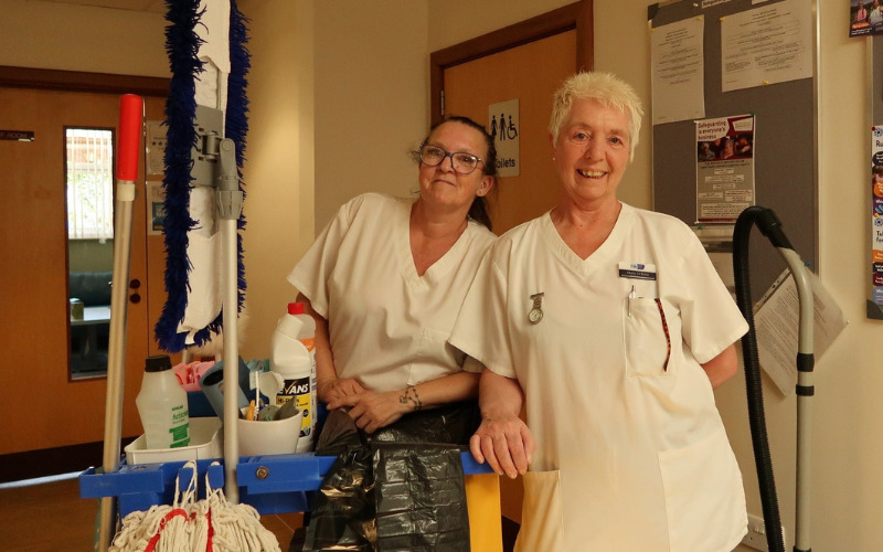 two-members-of-house-keeping-team-pose-with-cleaning-trolley