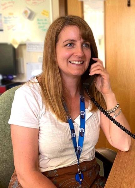 family-support-team-member-holds-phone-and-smiles (cropped)