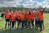 a-group-cheering-and-wearing-muddy-mayhem-medals-post-event