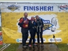 three-finishers-on-stage-holding-up-their-medals-at-the-isle-of-wight-ultra-challenge