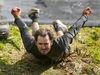 muddy-mayhem-participant-slides-down-muddy-bank-on-his-front